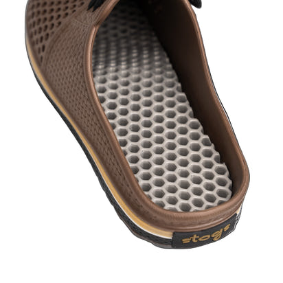 Close-up of a brown sandal with a textured sole on a white background