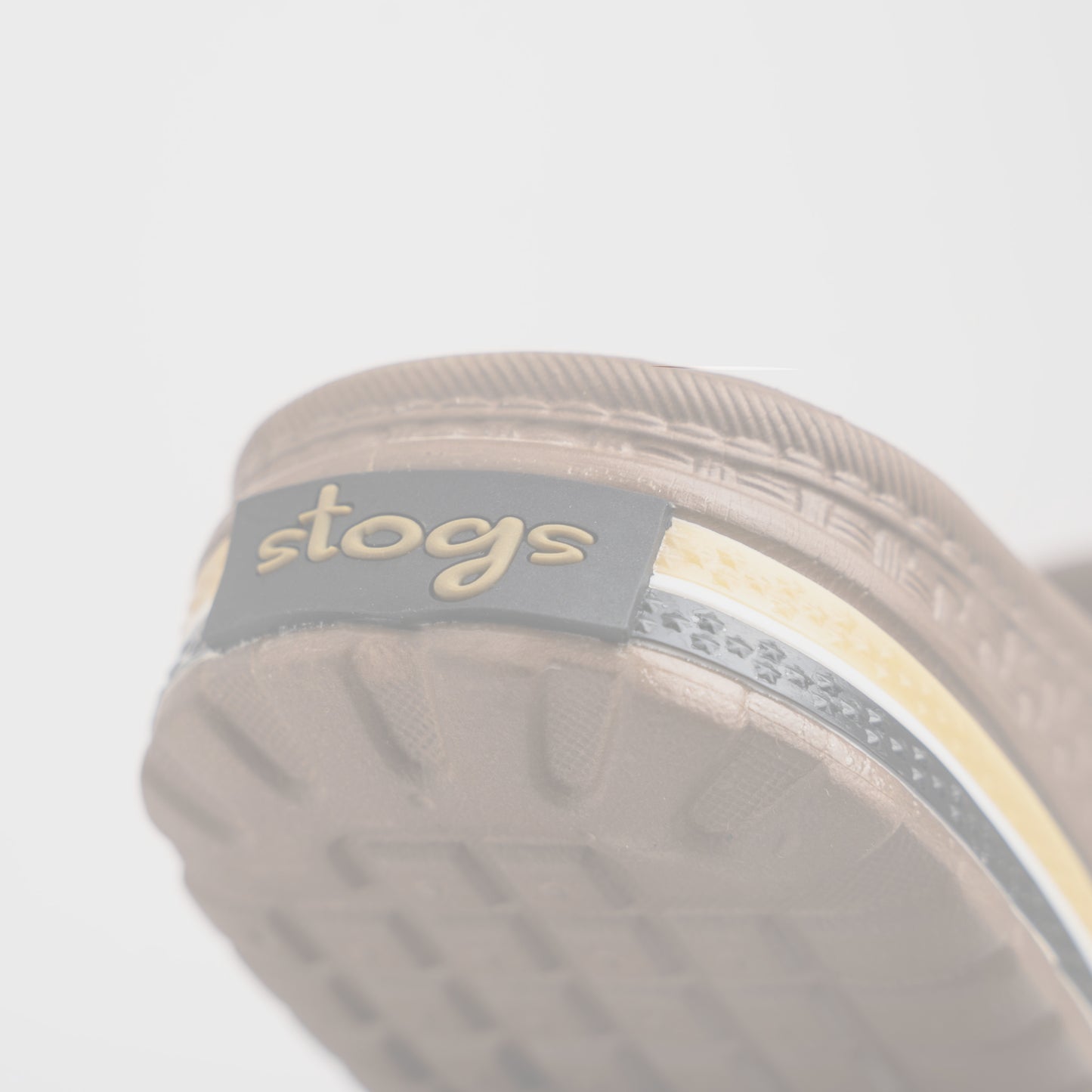 Close-up of a brown sandal sole with 'stogs' logo on a white background